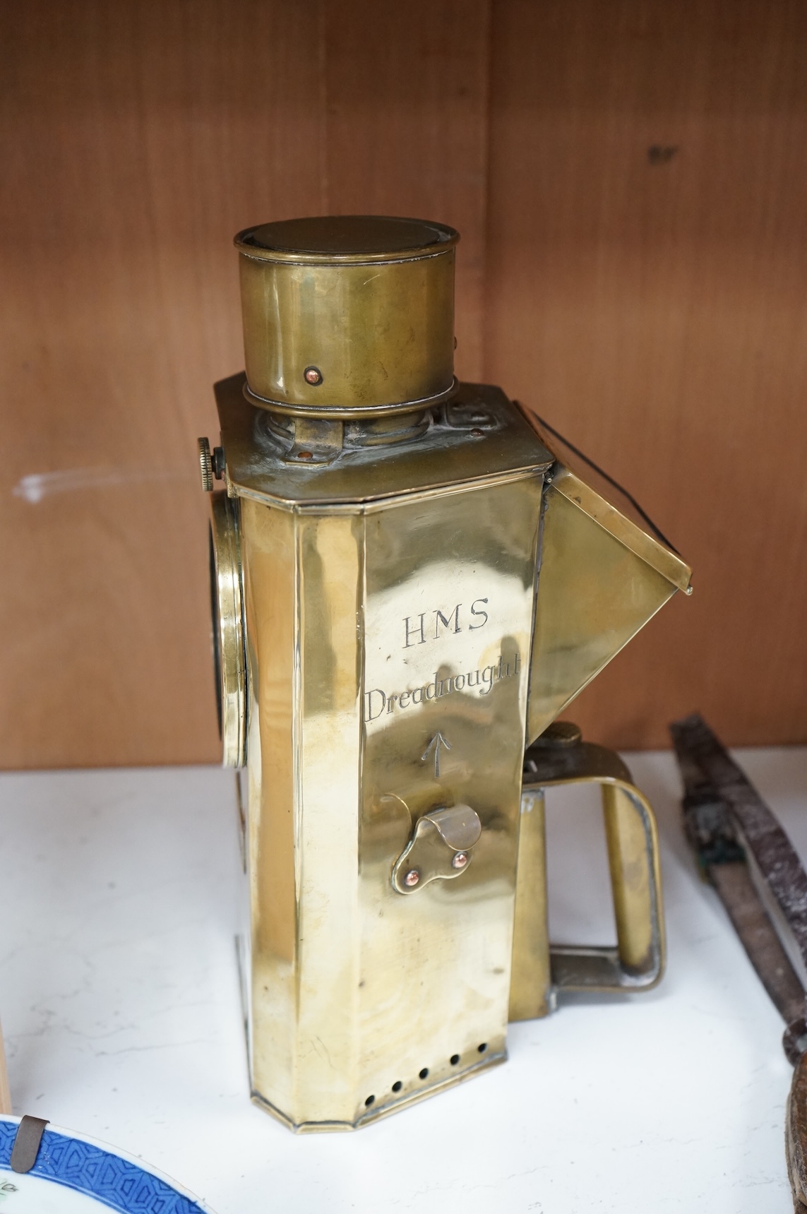 A naval brass Mitchell’s Patent morse code signalling lamp, numbered 24014 and dated 30 10 07, triangular body engraved ‘HMS Dreadnought’ to one face and ‘Admiral’s Barge’ to another, complete with burner and morse code